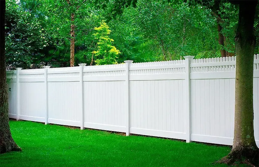 White vinyl fence in a green lawn setting with trees in the background.